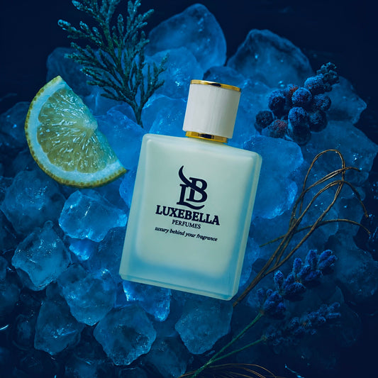 A bottle of Ice Mist Eau de Parfum by Luxe Bella sitting on a bed of crushed ice, surrounded by a slice of lemon, pine needles, lavender stems, and dark berries under cool blue lighting.
